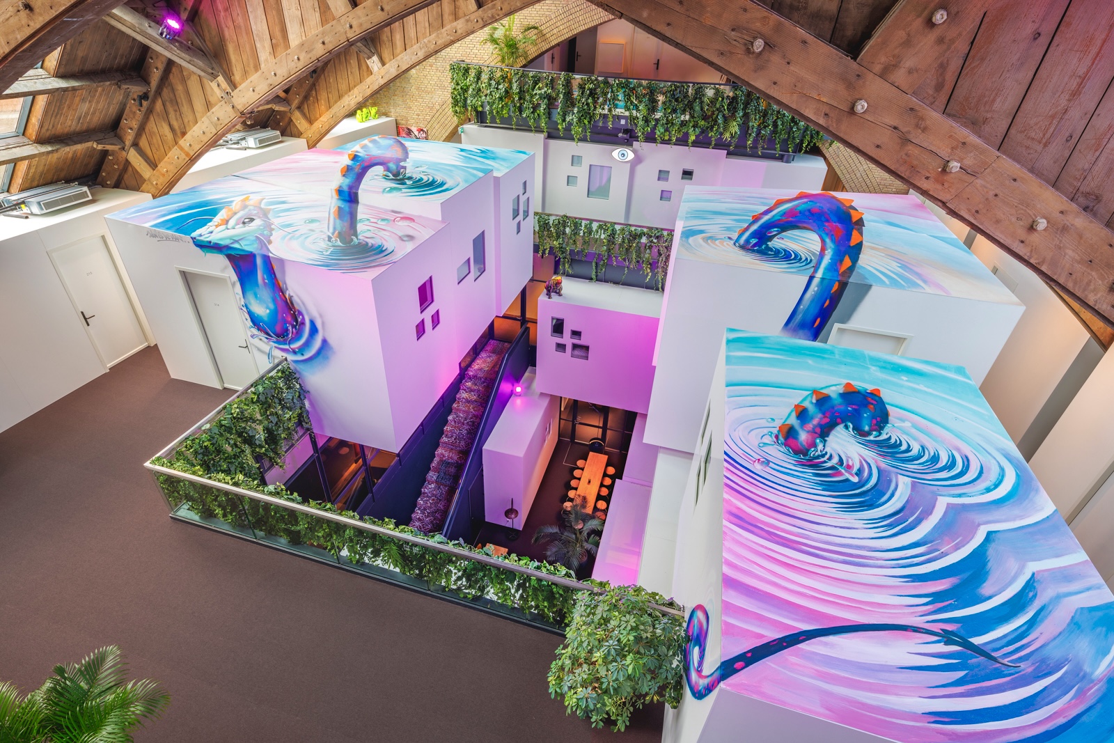 White cabin pods under a timber church roof, with a mural painted across their tops.