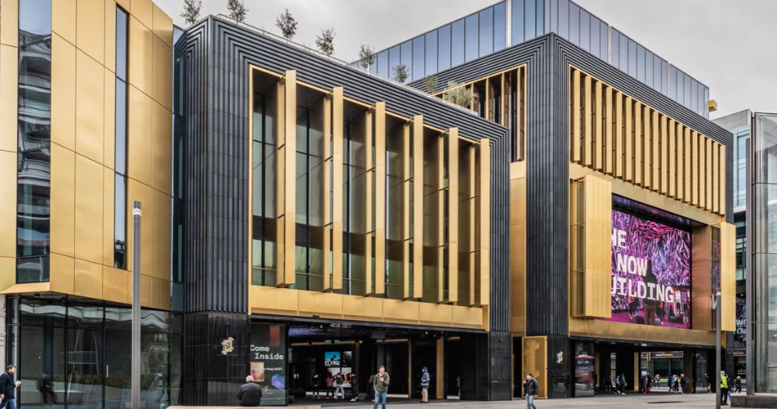 A gold and black city facade with vertical fins at street level.