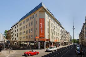 A corner city hotel building with the Berlin television tower in the distance.