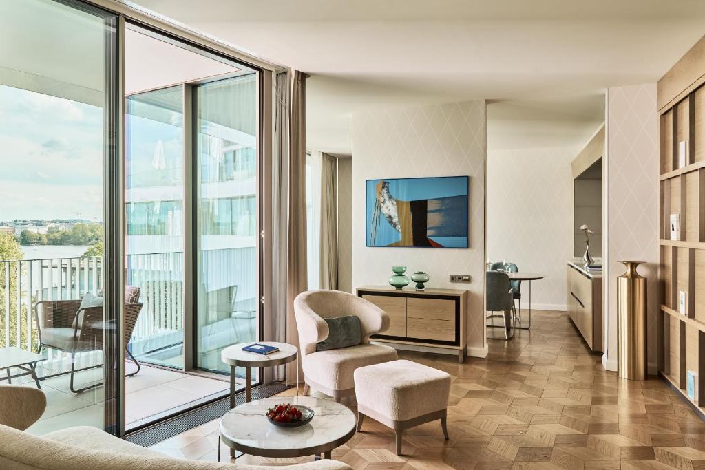 A hotel sitting room with a pale armchair, a balcony and a view over water.