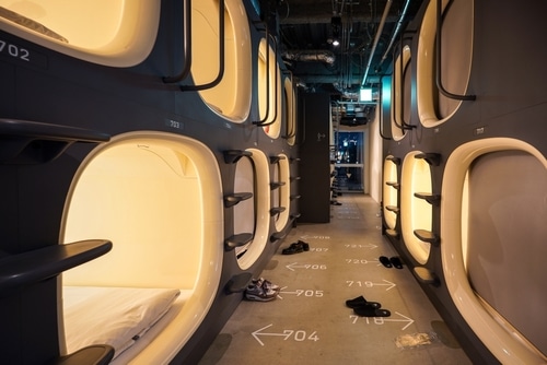 A corridor of stacked sleeping capsules with numbered units on both sides.